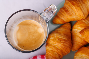 Elegant breakfast layout of fresh croissants and coffee on a light marble table, captured from a bird's-eye view for a stylish feel