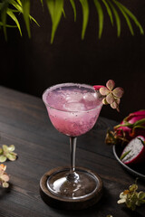 Refreshing dragon fruit cocktail garnished with tropical flower and ice cubes