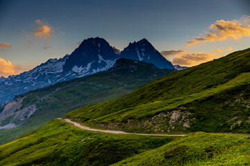 Naklejka premium Sunset burning red and orange sky above the snow summits and rocky peaks of the Alps. Beautiful mountain sunset and sunrise in Chamonix valley on the ascent to Montblanc
