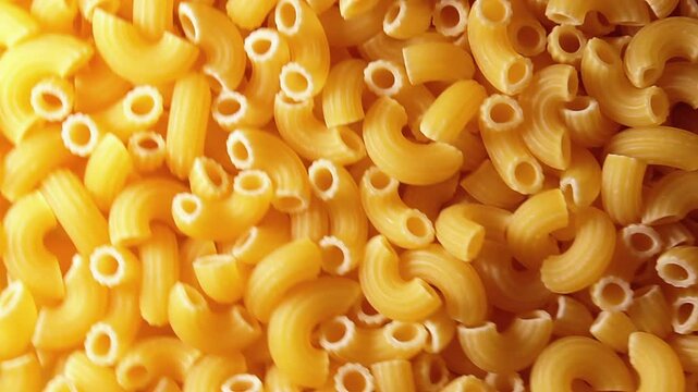 Uncooked Chifferi Rigati Pasta - Top View. Fat and Unhealthy Food. Classic Dry Macaroni, Slowly Rotating Background. Italian Culture and Cuisine. Raw Golden Pasta Texture - Left Angular Rotation