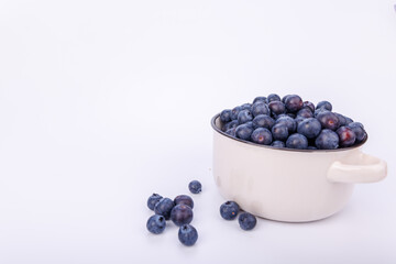 Small ceramic pot overflowing with blueberries on a pure white background, creating a crisp and fresh visual of healthy fruit in a minimalist style