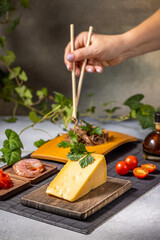 Woman using chopsticks while eating soba noodles with cheese, shrimp and tomatoes