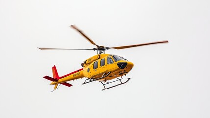 Fototapeta premium A yellow helicopter with a red tail is flying in the air. The background is white.
