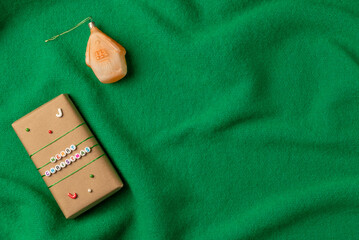 Merry Christmas gift box on green knitted background from above. Flat lay, top view.