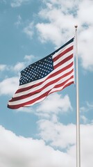 Fototapeta premium The flag of the United States flutters in the wind, showcasing its colors and symbols under a bright, clear sky, embodying national pride