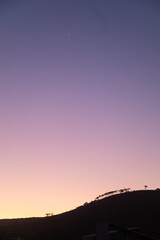 Dusk over a silhouetted hill with trees