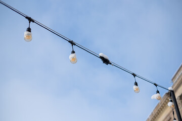Obraz premium Winter string lights covered in snow against a clear blue sky in an urban setting in the afternoon hours