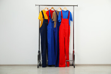 Workers' uniforms on clothing rack near grey wall indoors