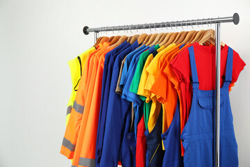 Workers' uniforms on clothing rack near grey wall indoors. Space for text