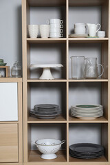 Wooden shelving unit with kitchenware near grey wall indoors