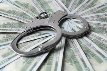 Corruption. Handcuffs on dollar banknotes, closeup view