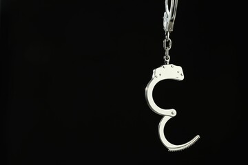 Metal chain handcuffs on black background, closeup. Space for text