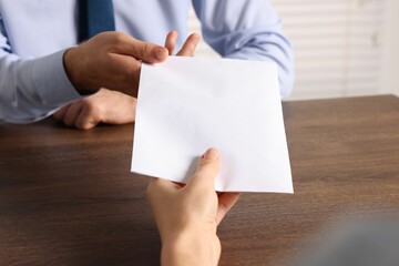 Corruption concept. Woman giving envelope with money to man at wooden table, closeup