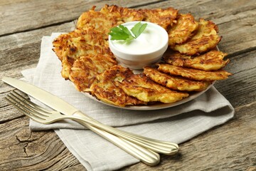 Delicious potato pancakes served on wooden table, closeup
