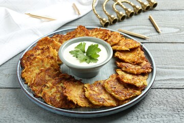 Delicious potato pancakes, menorah and candles on gray wooden table, closeup. Hanukkah festive food