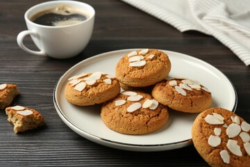 Tasty cookies with almond flakes and coffee on wooden table, closeup