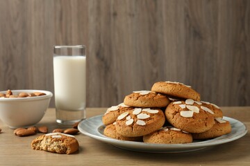 Tasty cookies with almond flakes, nuts and milk on wooden table