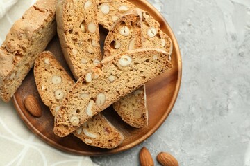 Traditional Italian almond biscuits (Cantucci) and nuts on grey textured table, flat lay. Space for text