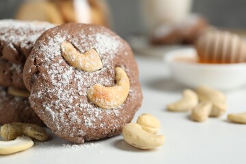 Tasty chocolate cookies with cashew and powdered sugar on white table, closeup