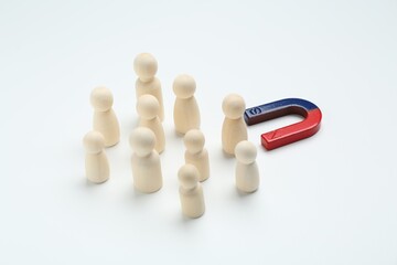 Magnet attracting human figures on white background, closeup
