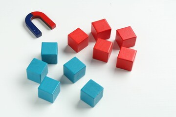 Magnet attracting colorful cubes on white background