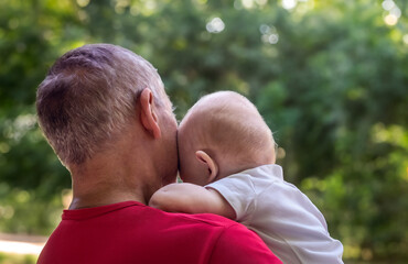 grandfather holding grandson in arms, close up portrait of elderly man and 10 month old boy