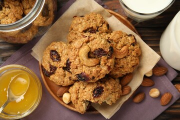 Delicious oatmeal cookies with raisins and nuts served on wooden table, flat lay