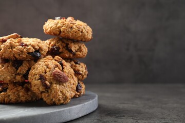 Delicious oatmeal cookies with raisins and nuts on grey table, closeup. Space for text