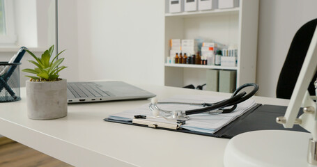 Close up doctors desk with medicat tools and laptop. Stethoscope on the desk in a hospital. Medical content.