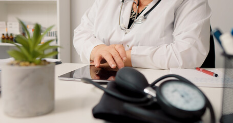 Woman doctor using technology to consult people remotely on tablet. Medical worker answering to patients online.