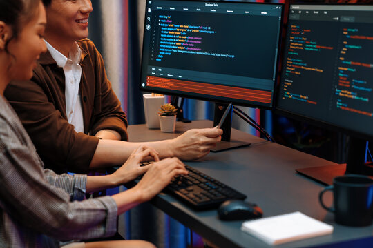 IT developers discussing with point to intelligent website development coder system running data online two screens information technology at neon light room at modern office. Infobahn.
