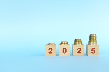 Lucky year 2025 invest and grow money business concept. Increasing stack of coins in wooden blocks.	