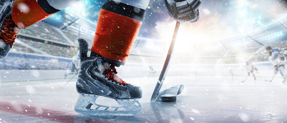 Hockey skates, stick and puck close-up. Hockey player in ice arena. Focus on the puck. Hockey player in action. Ice. Hockey stadium