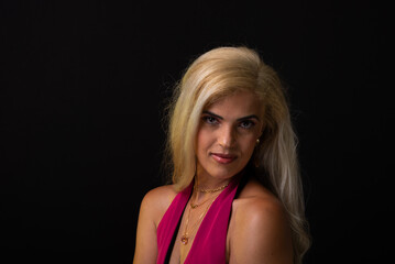 beautiful caucasian woman with blond hair in red dress posing and looking at camera isolated on black background. Studio in the city of Salvador, Bahia.