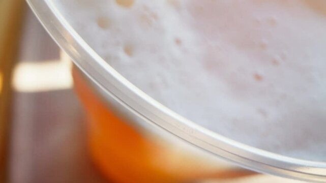 Camera movement to beer foam in a plastic cup
