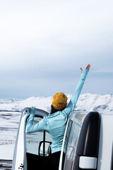 Fototapeta premium Woman reaching out from vehicle in snowy landscape