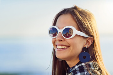 Happy woman, sunglasses and freedom with fashion or jewelry in nature for holiday, weekend or outdoor vacation. Young, female person or tourist with smile in joy for stylish accessory or carefree day