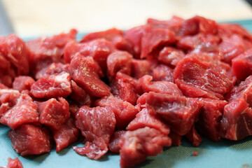 Close up of red raw beef meat chopped in small cubes on cutting board