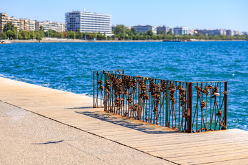 A metal fence with locks on it is sitting on a pier next to the ocean