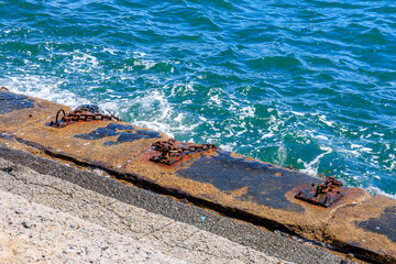 A rocky shoreline with a chain link fence and a chain link railing