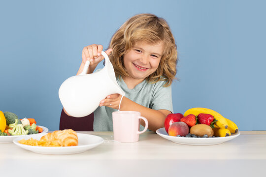 Closeup face of kid eating organic food, yogurt, milk. Child healthy eat. Smiling little boy eating food on kitchen. Kid with dairy milk. Healthy child pours milk from jug.