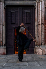 Naklejka premium middle aged tai chi master showing stick exercises outdoors amidst the architecture of a medieval cathedral