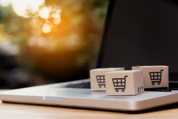 Shopping online. Cardboard box with a shopping cart logo on laptop keyboard. Shopping service on...