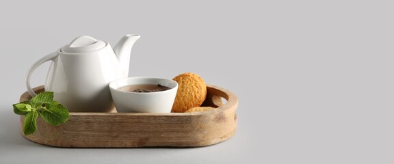 Composition with tea pot, cup and cookies on grey background with space for text
