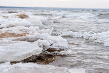 Ice formations line the shore during early spring at a lake, showcasing the transition from winter...