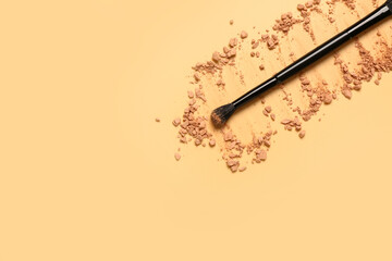 Makeup brush and facial powder on yellow background