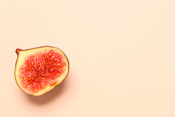 Half of fresh juicy fig on pale pink background