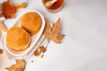 Plate of tasty pancakes with nuts and maple syrup on white background