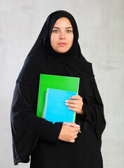 calm , focused student girl with stack of large multicolored notebooks. Muslim female student...