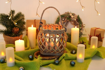 Burning candles with Christmas tree and wreath on table, closeup